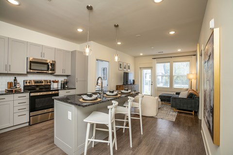 a kitchen and living room with a bar and chairs